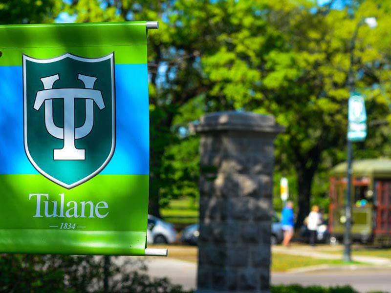 Tulane shield on a flag with trees in the background